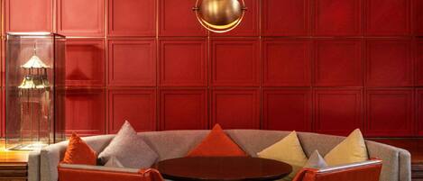 A red-walled room with a round table and red and grey chairs.