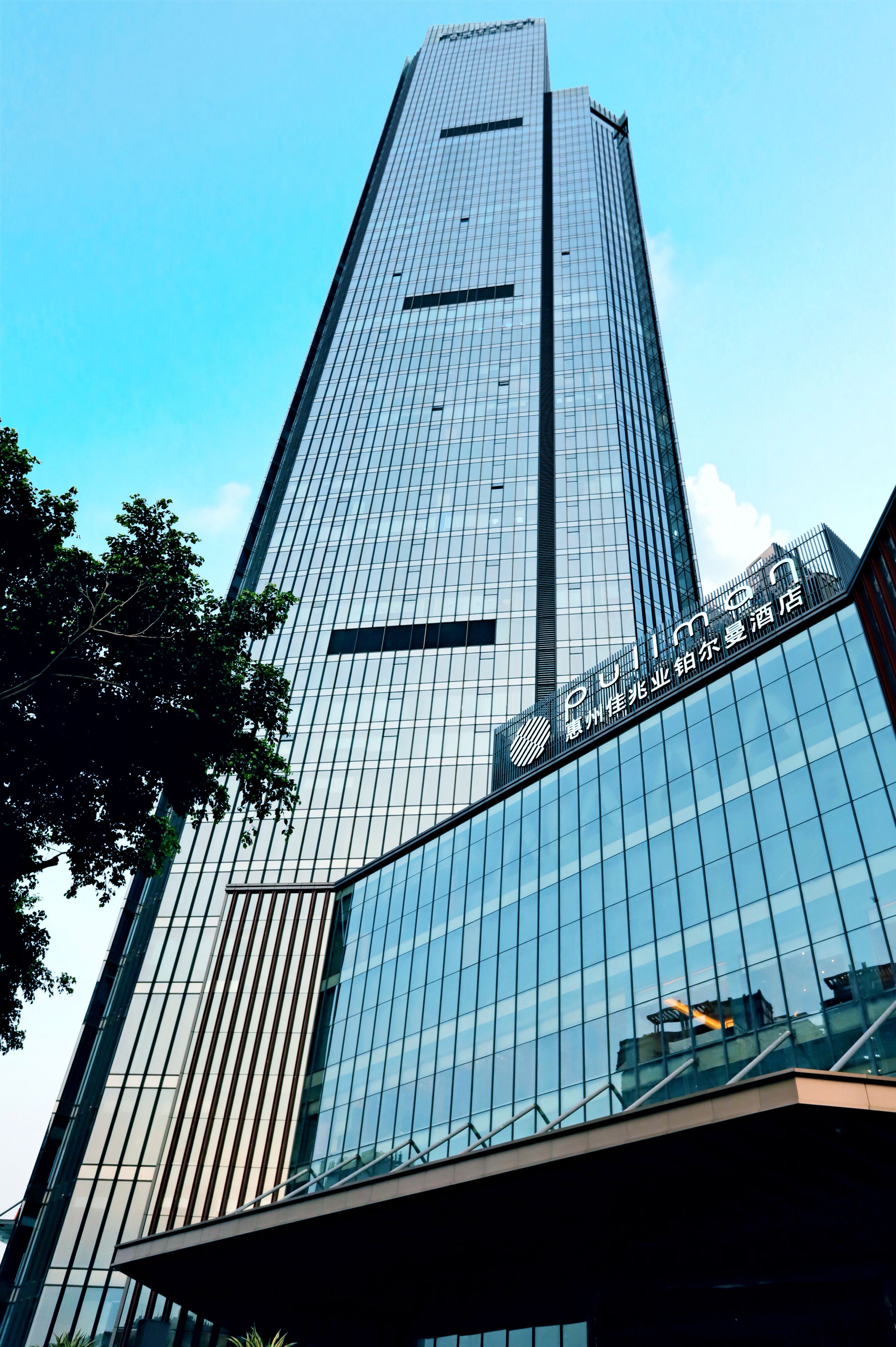 A tall, modern skyscraper with a glass facade and a prominent sign at the top.