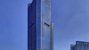 A tall, modern skyscraper with a reflective glass facade and a prominent vertical line running down its center.