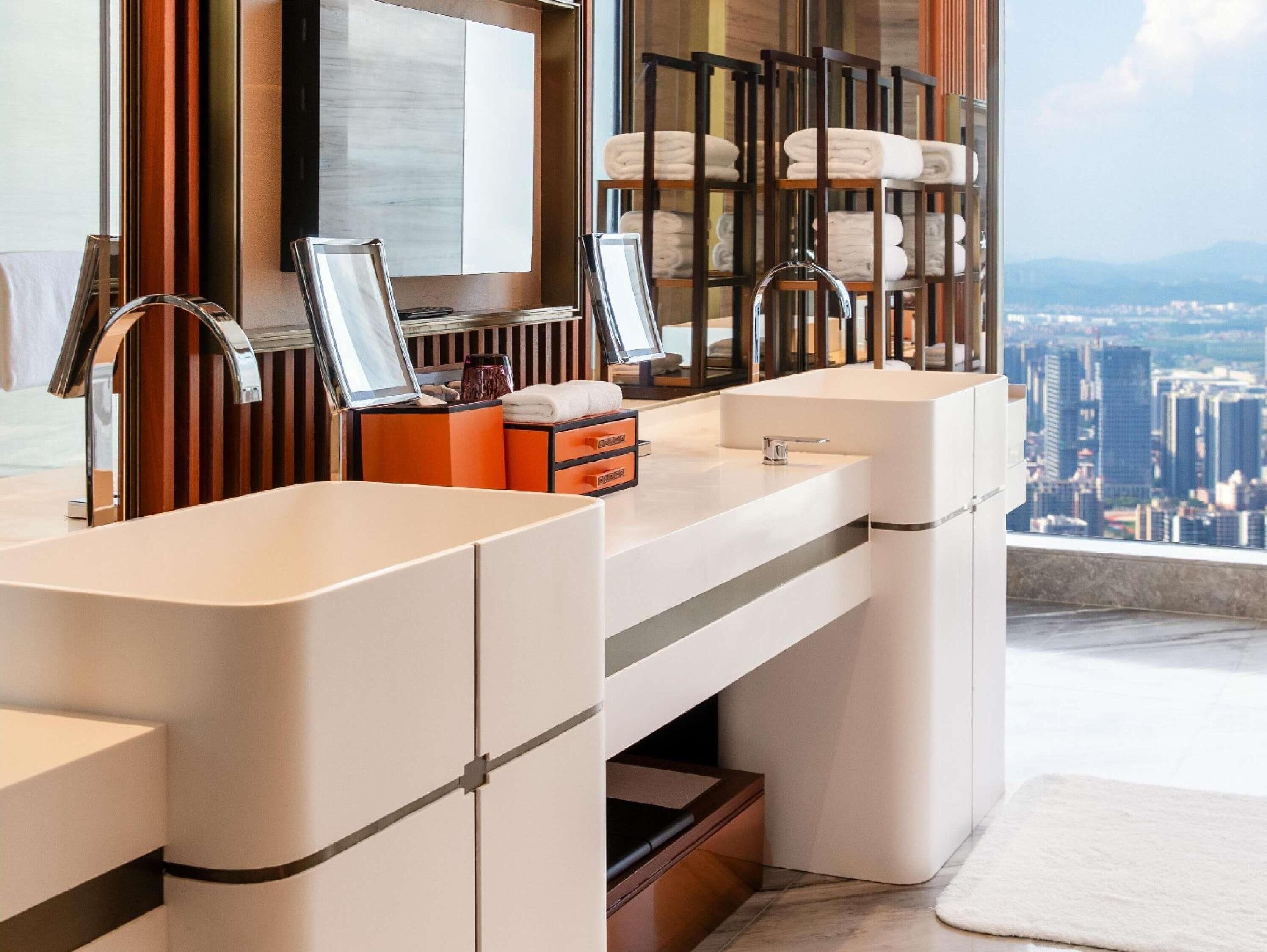 Une salle de bain moderne avec deux vasques, un grand miroir et un porte-serviettes.
