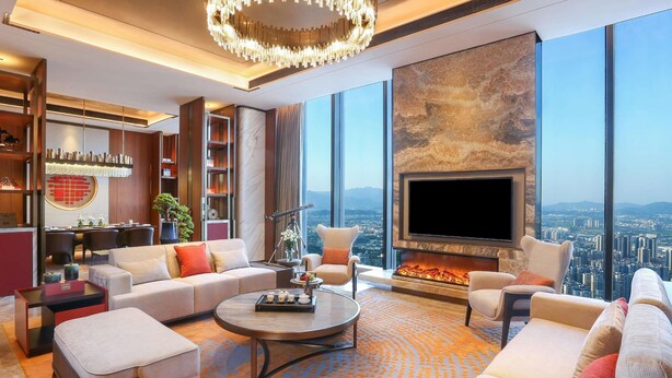 A modern living room with a fireplace, large windows, and a city view.
