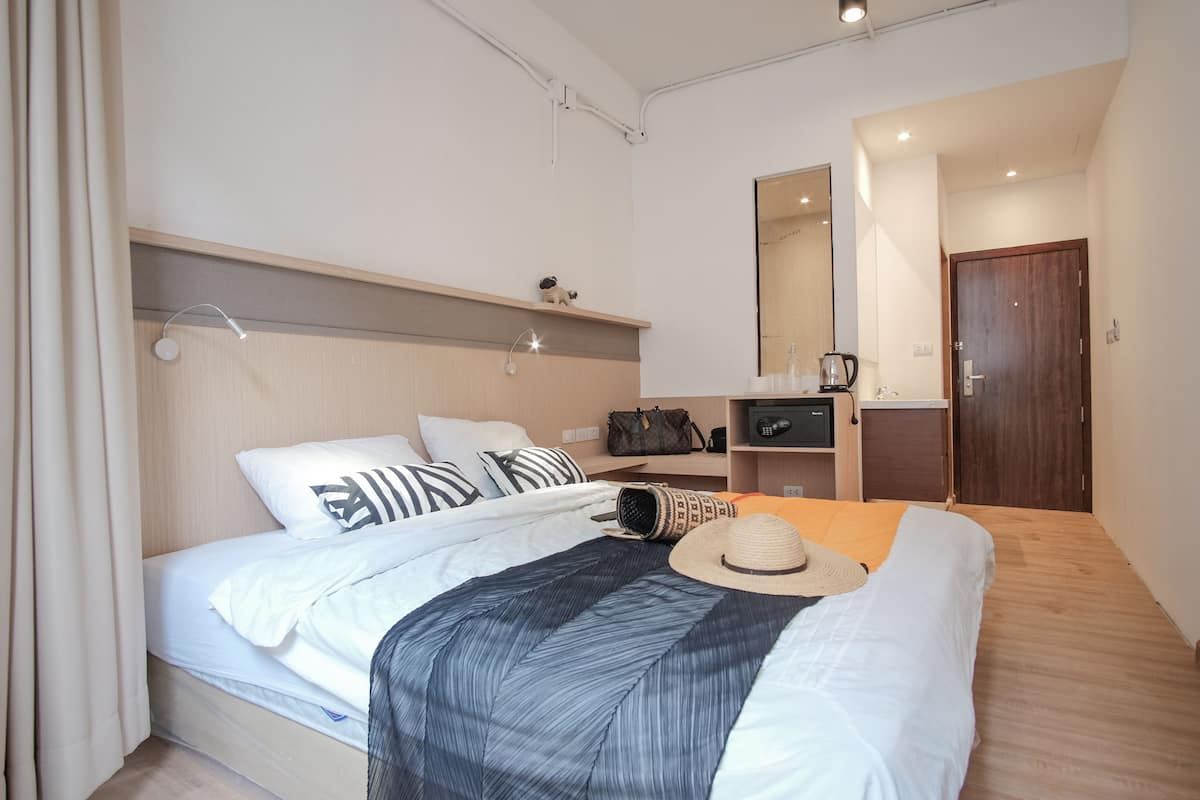 A modern bedroom with a bed, bedside table, and a mirror.