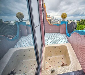 Terraço no telhado com banheira de hidromassagem, azulejos estampados e esferas decorativas.
