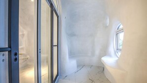 A narrow hallway with a glass door leading to a room, a curved wall, and a small window. - Wien Art Villa (Liuqiu)