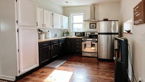 A kitchen with white cabinets, a stainless steel refrigerator, a microwave, and a stove. - Family-friendly, stylish Chicago Apartment in Logan Square (Chicago)