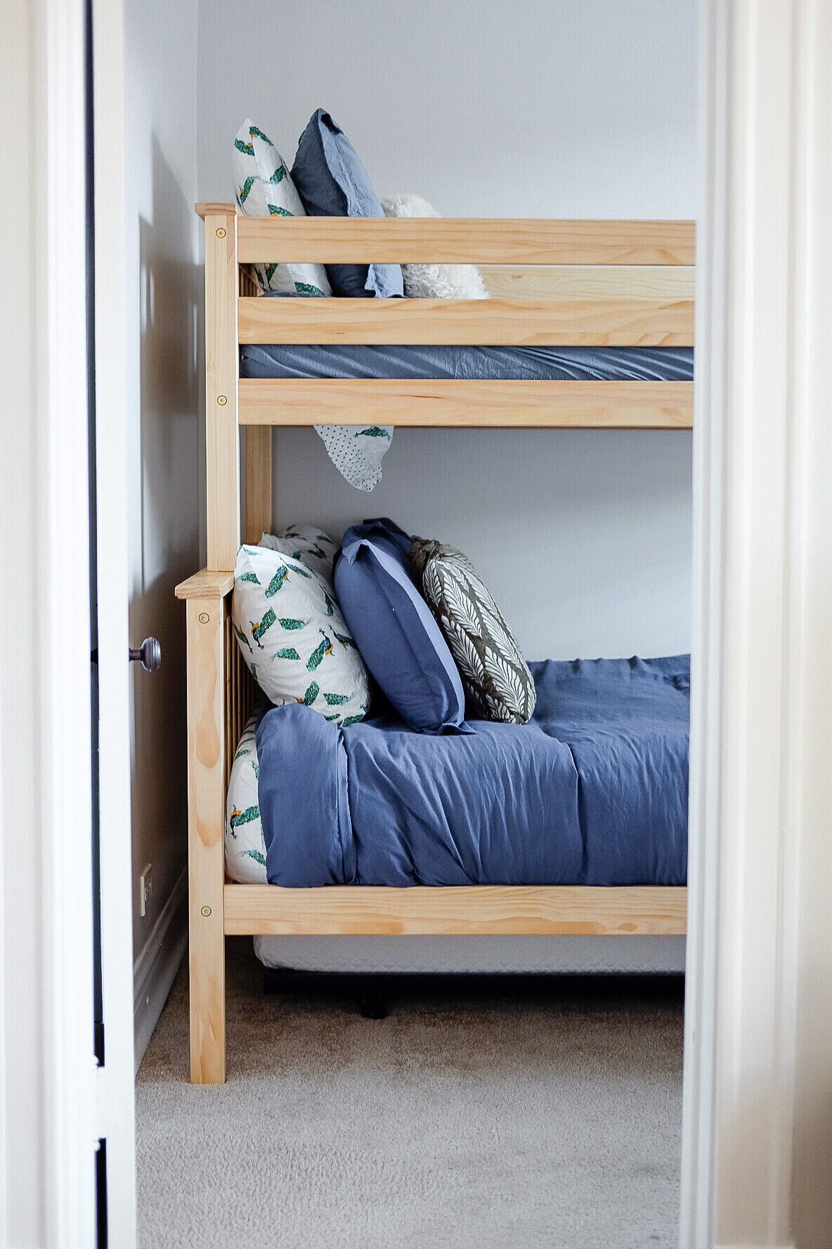 A bunk bed with a blue mattress and patterned pillows.