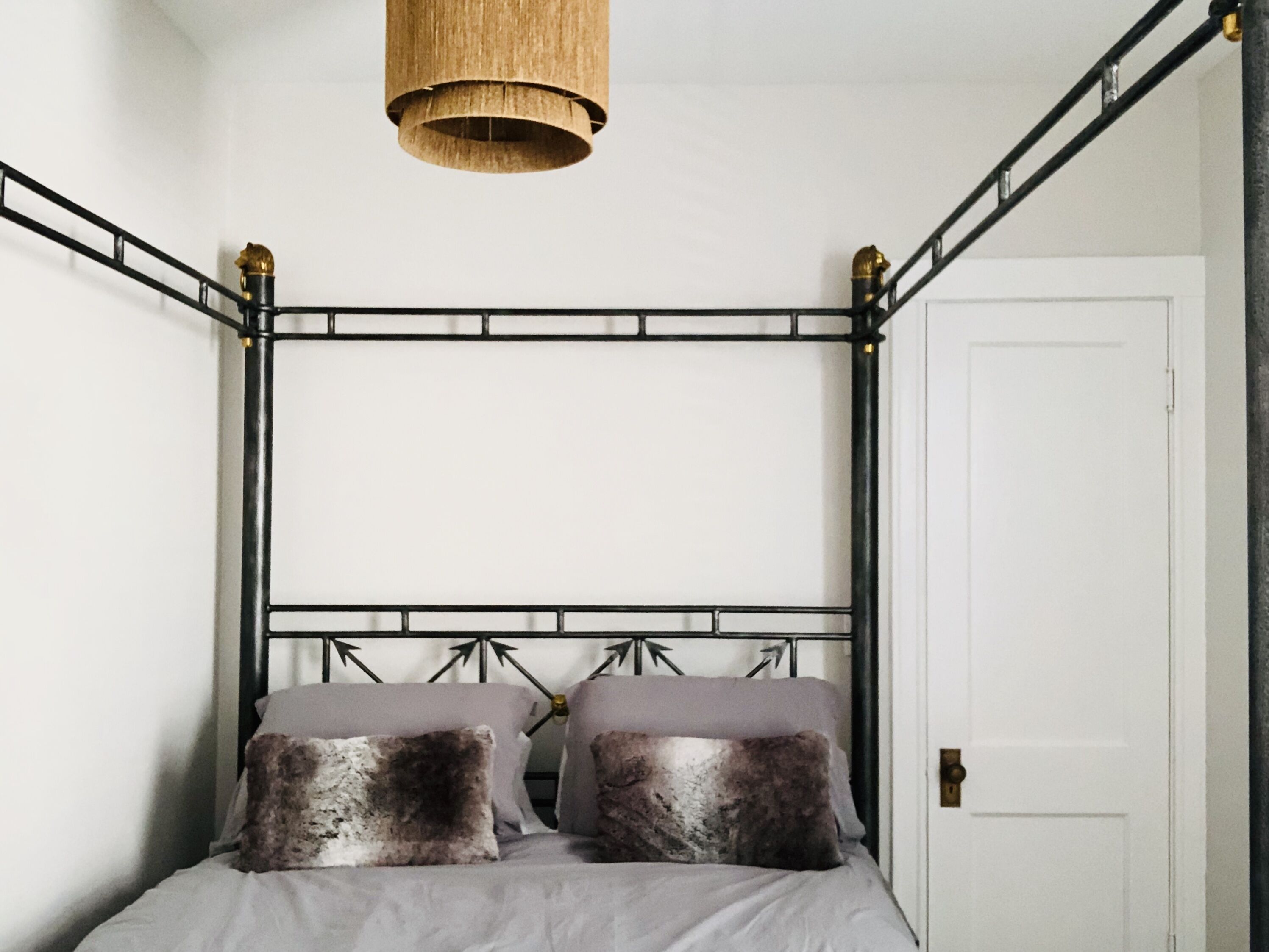 Una cama con dosel de estructura metálica y cabecera de madera.
