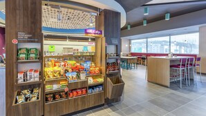 Un quiosco de aperitivos con diversas opciones de comida empaquetada y un letrero que anuncia un mercado abierto las 24 horas.