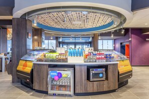 Un kiosque moderne en libre-service, doté d’un présentoir réfrigéré, d’une machine à café et d’une variété de collations.