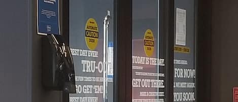 A hotel entrance with glass doors, a reception desk, and a sign indicating 'Today is the day' and 'Get out there'.