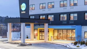 Un hotel moderno con entrada despejada, un letrero que indica 'tru by Hilton', y un área cubierta con pilares.