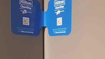 A door with a blue card attached to it, featuring the Hilton CleanStay logo and a QR code.