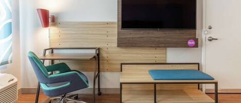 Una habitación de hotel con una cama, un escritorio, una silla, un televisor y una puerta.