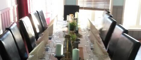 A long dining table set for a meal with chairs on both sides, candles, and a menu.