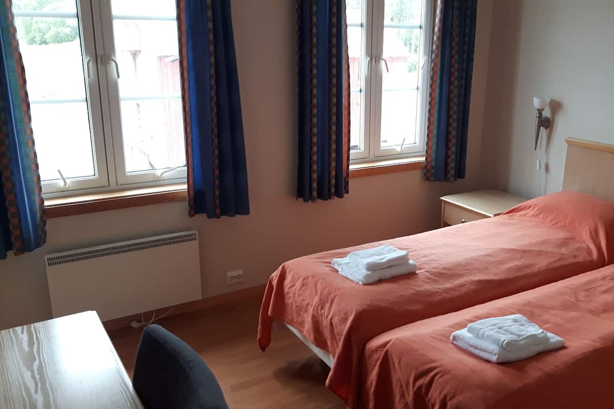 Een hotelkamer met twee bedden, een bureau en een raam met gordijnen.
