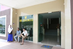 A building entrance with a glass door, a phone number, and a sign indicating the building is open. - Hotel Alor Villa (Alor Gajah)