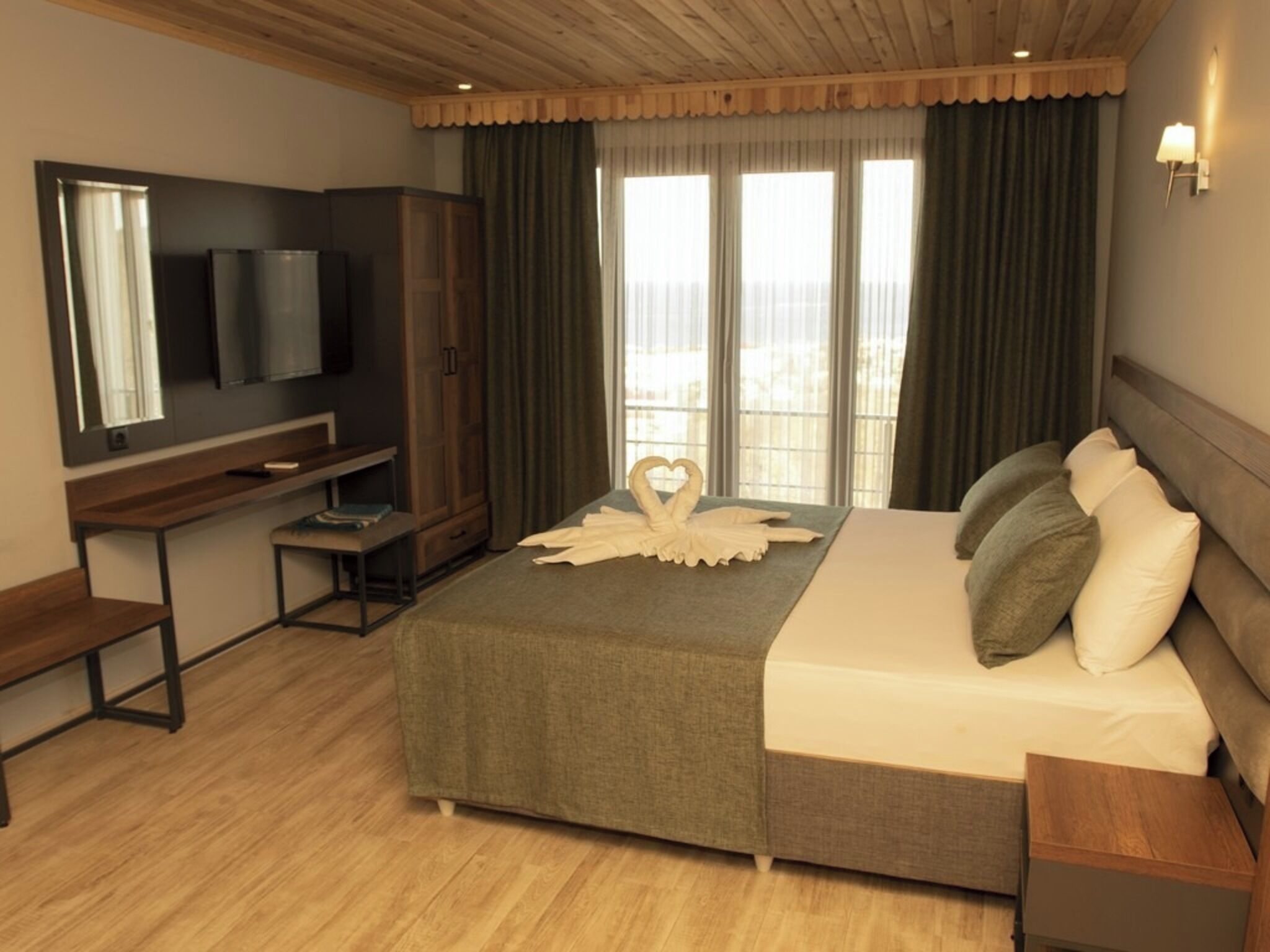 Ein Hotelzimmer mit Bett, Fernseher, Schreibtisch und einem Fenster mit Vorhängen.