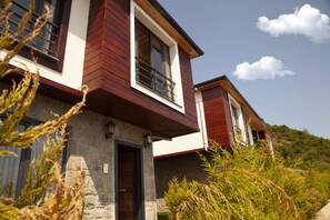 A two-story house with a stone facade, a balcony, and a view of a hill. - Royal Villa (Arsin)
