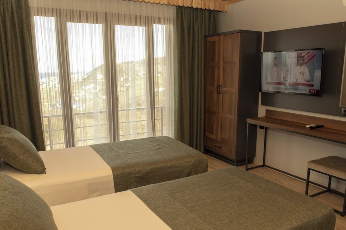 A hotel room with two beds, a desk, a television, and a wardrobe.