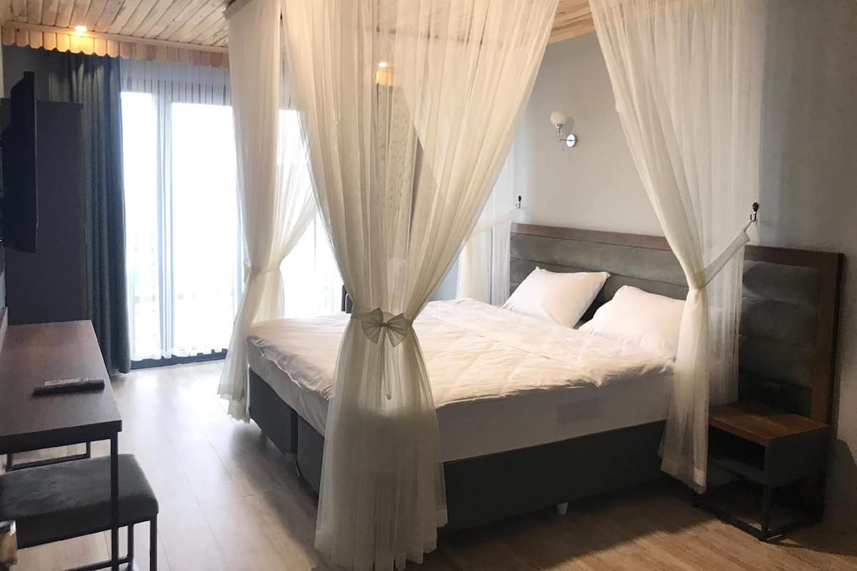A bedroom with a four-poster bed, a desk, and a chair.