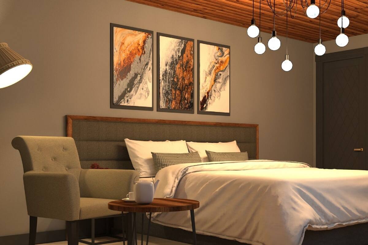 A bedroom with a bed, a chair, a small table, and artwork on the wall.