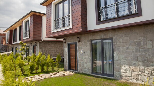 Una hilera de casas modernas con fachadas de piedra y detalles de madera.