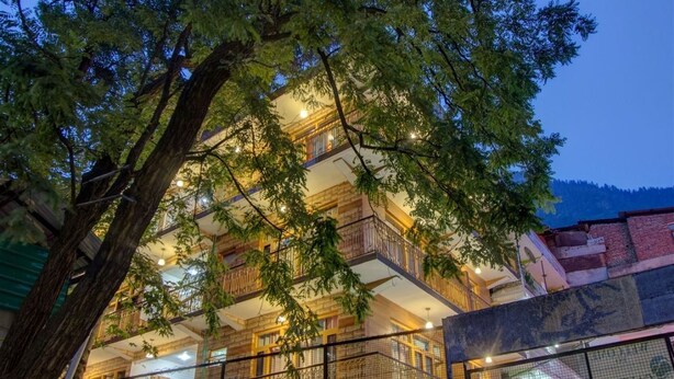 A multi-story building with balconies, surrounded by trees and a fence. - Hotel Samiru (Manali)