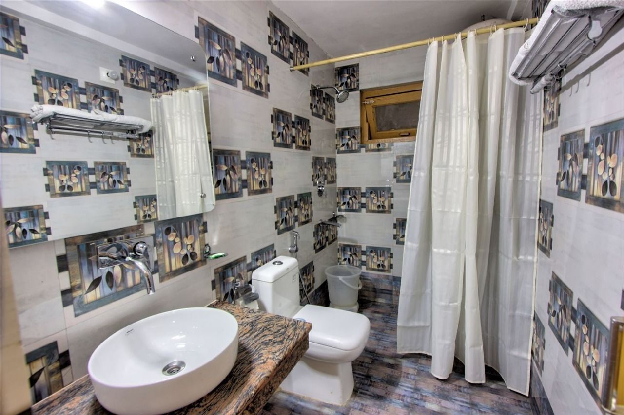 A bathroom with a sink, toilet, shower, and a mirror.