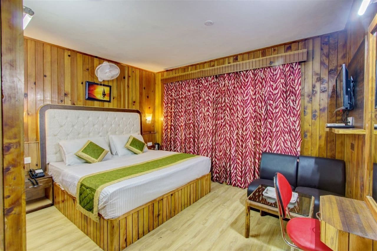 A room with a bed, a sofa, a small table, and a TV mounted on the wall.