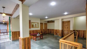 A spacious lobby with wooden paneling, a central seating area, and a staircase. - Hotel Samiru (Manali)