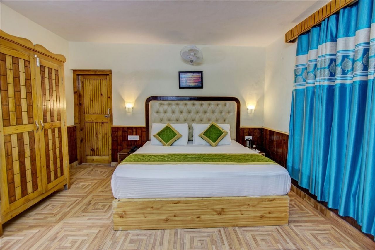 A bedroom with a large bed, wooden wardrobe, and a blue curtain.