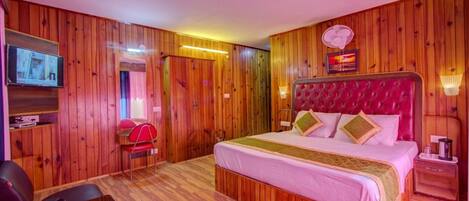 A wooden-paneled room with a bed, a TV, a table with a tray, and a chair.