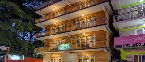 A multi-story hotel with balconies, a sign for 'Hotel Samiru', and parked vehicles.