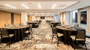 A conference room with multiple tables, chairs, and a large screen. - Canvas Moncton, Tapestry Collection by Hilton (Moncton)