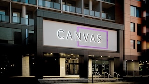 A building with a prominent 'CANVAS' sign, featuring a modern architectural style with a balcony and a glass facade. - Canvas Moncton, Tapestry Collection by Hilton (Moncton)