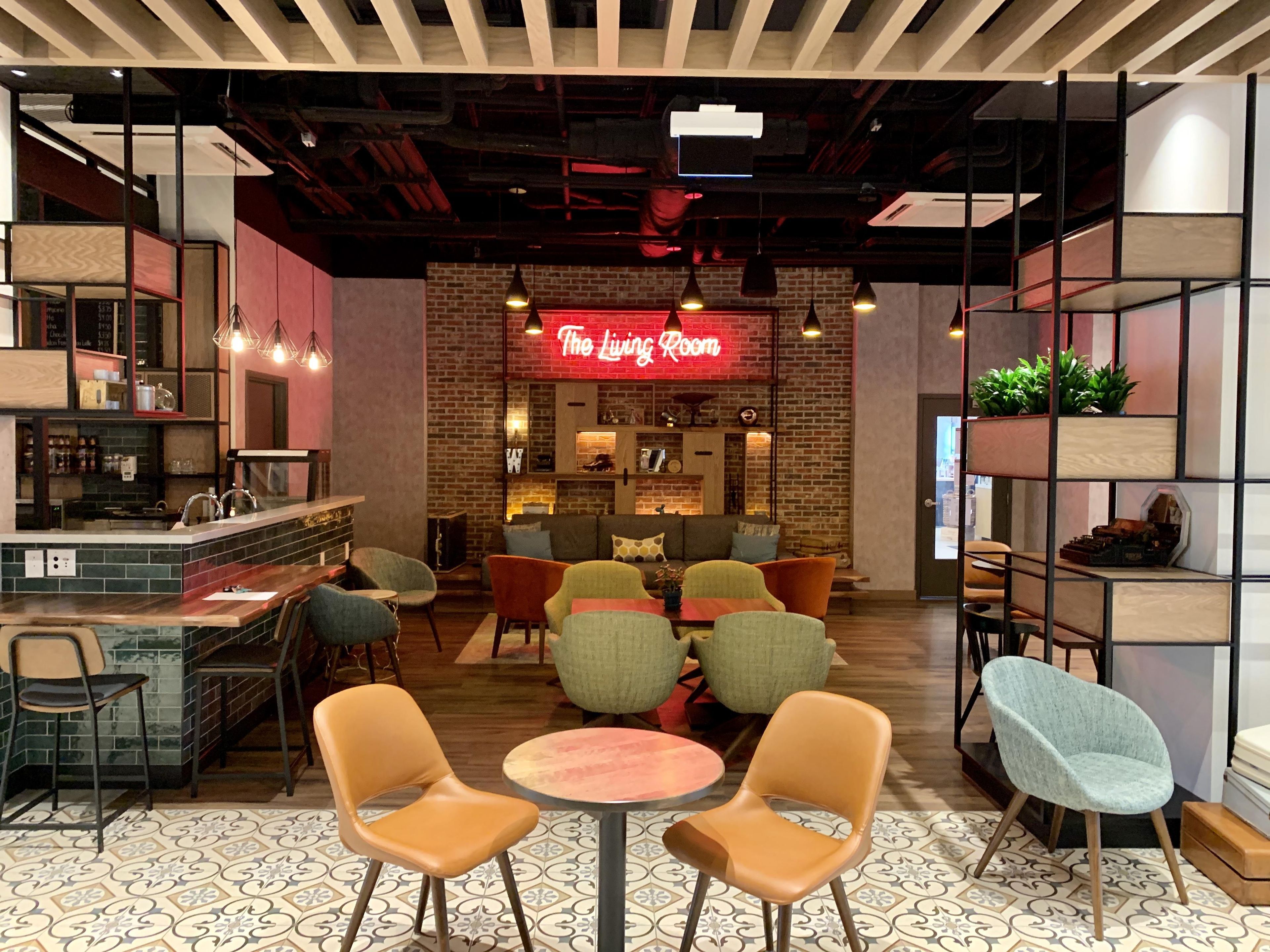 A modern interior with a bar area, seating, and a neon sign reading 'The Living Room'.