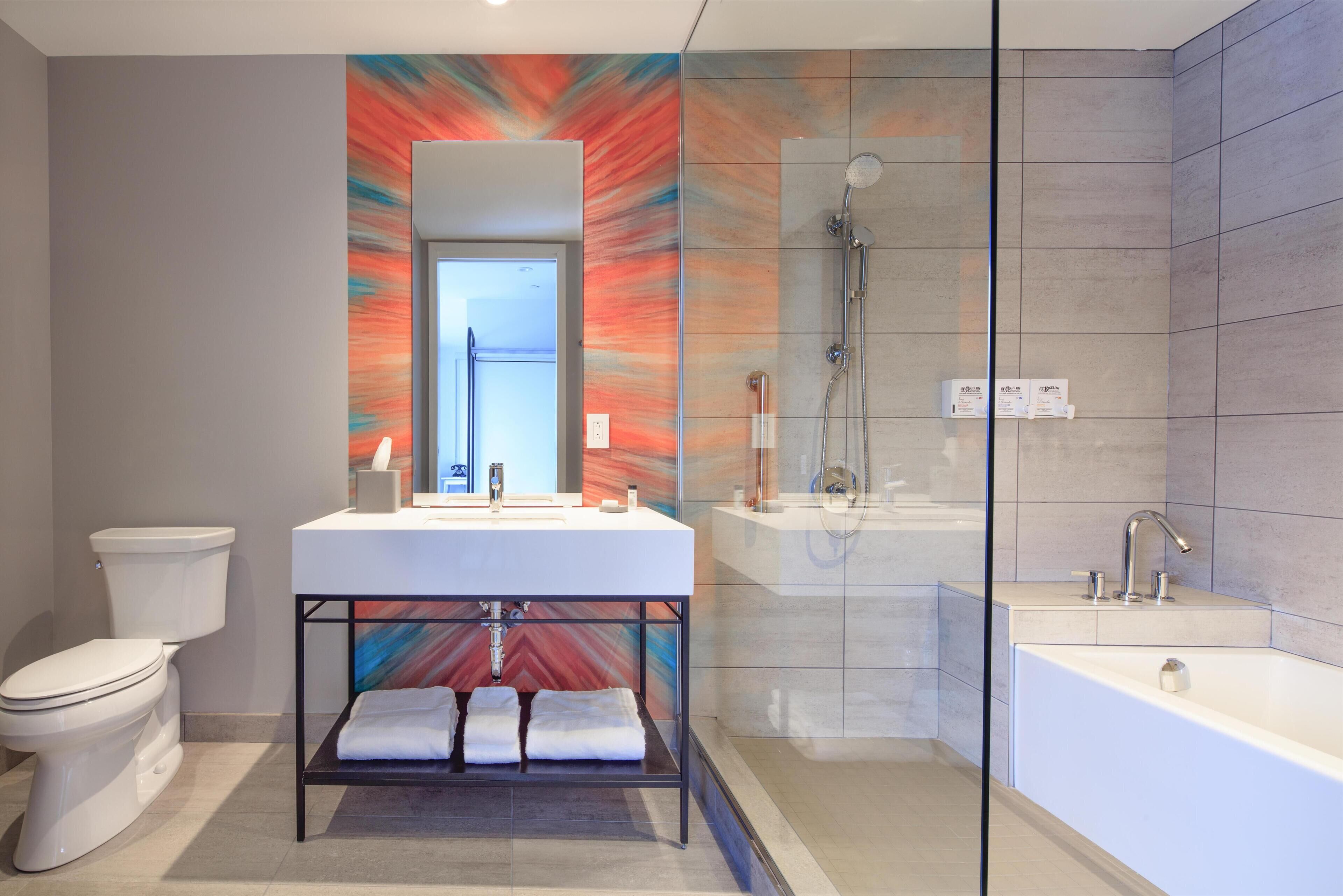 Een moderne badkamer met een witte wastafel, een douche met glazen wanden en een grote spiegel.