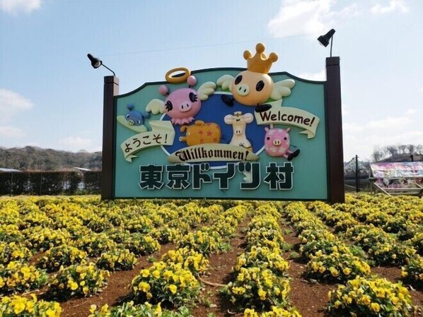 A sign with cartoon characters and the text "Welcome! Willkommen! Willkommen! 東京ドーム村".