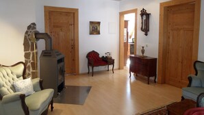 A living room with a fireplace, wooden doors, a red armchair, a wooden cabinet, and a blue armchair.