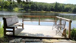 Une jetée en bois, avec un banc et une rambarde en métal, donnant sur un lac.