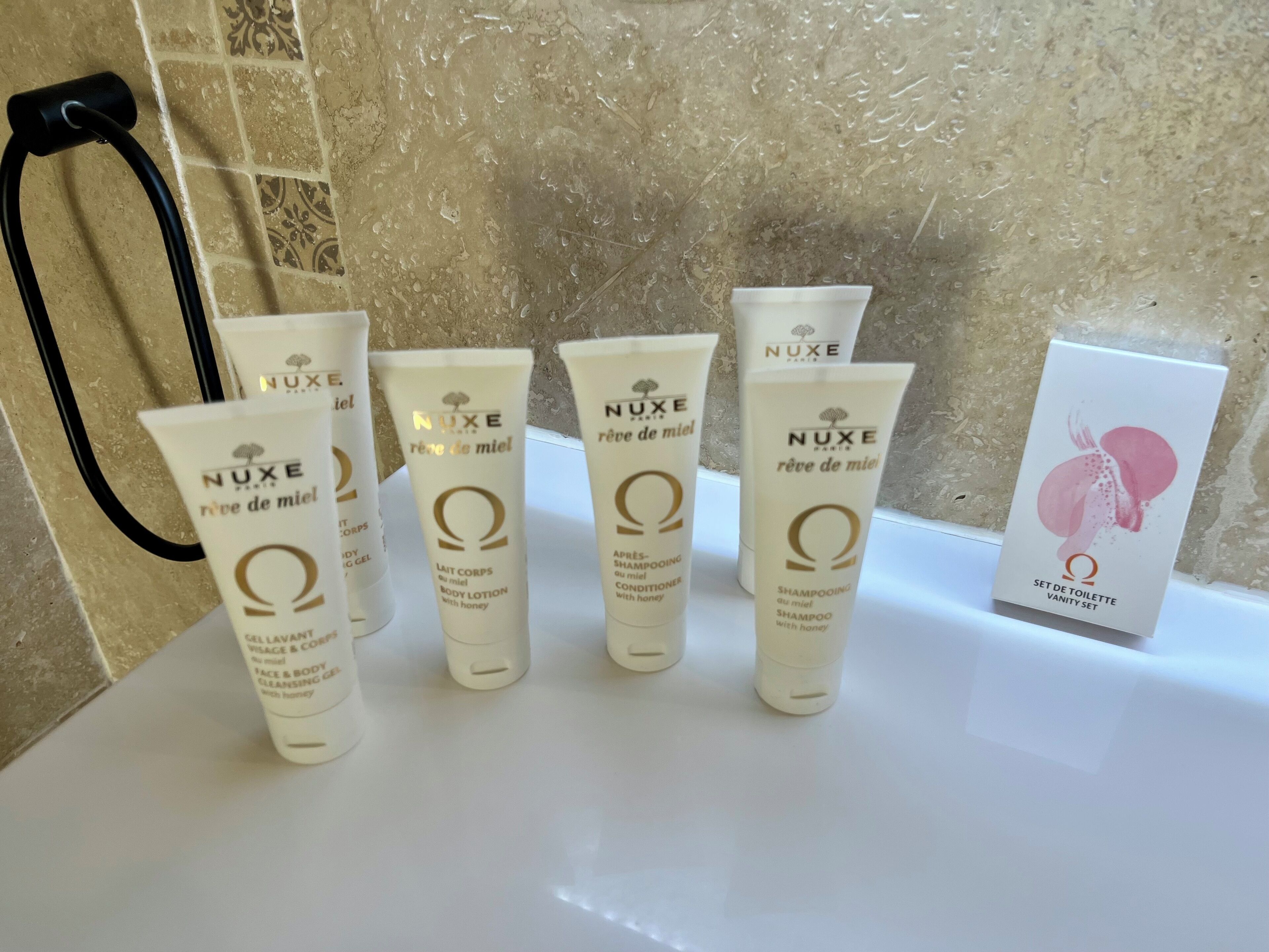 Une salle de bain équipée de produits de toilette, notamment une lotion pour le corps, un shampooing et un ensemble de produits de beauté.