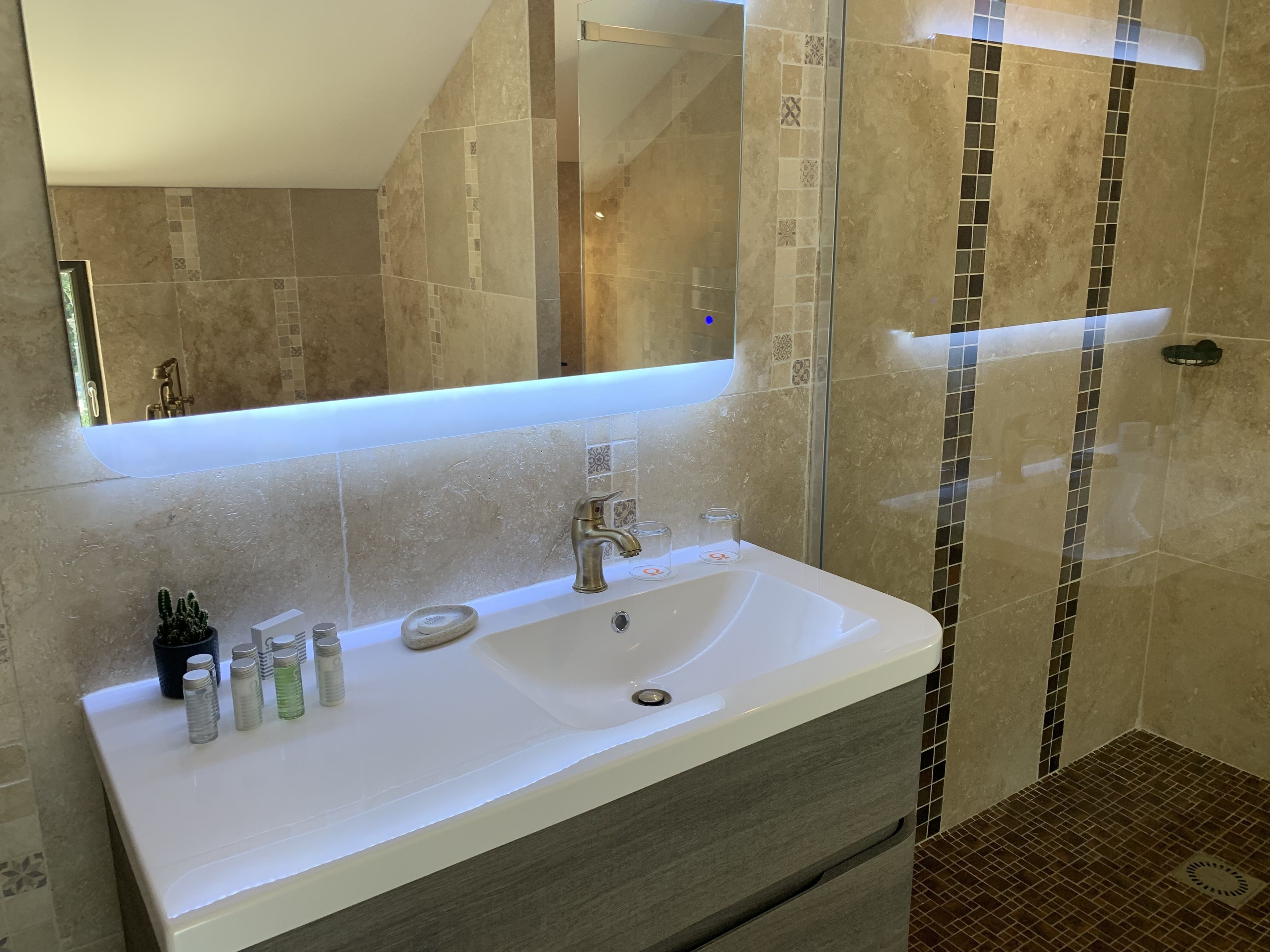 A bathroom with a large mirror, a sink, and a shower area.