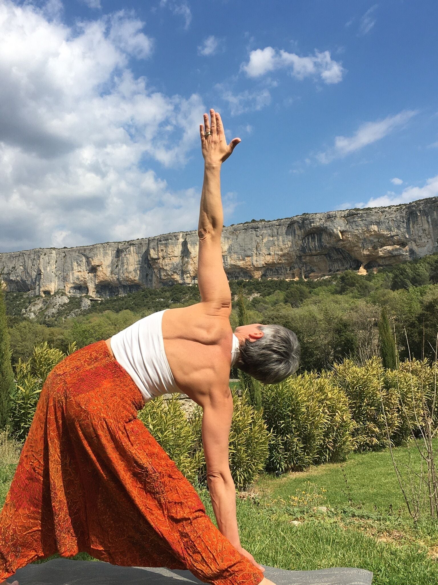 A person performing a yoga pose outdoors with a mountainous landscape in the background.