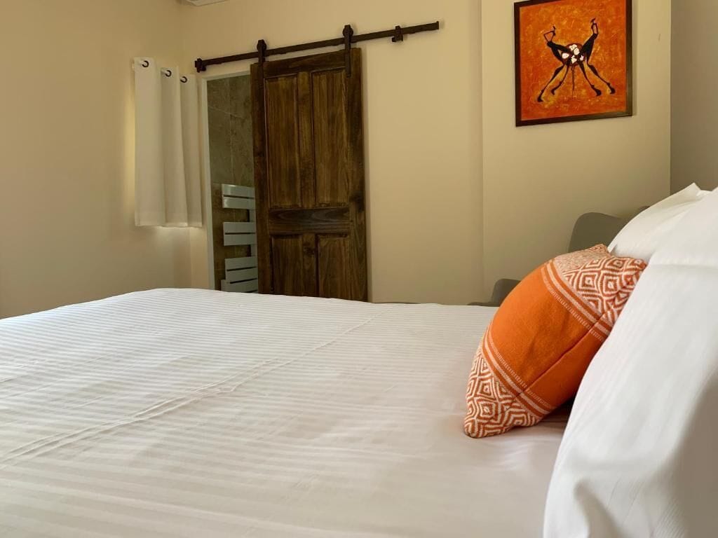 A bedroom with a bed, a wooden wardrobe, a sliding door, and a framed artwork on the wall.