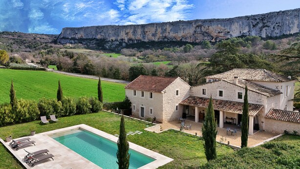 A stone villa with a swimming pool, surrounded by lush greenery and a mountainous backdrop. - Le Mas aux cedres (Lioux)