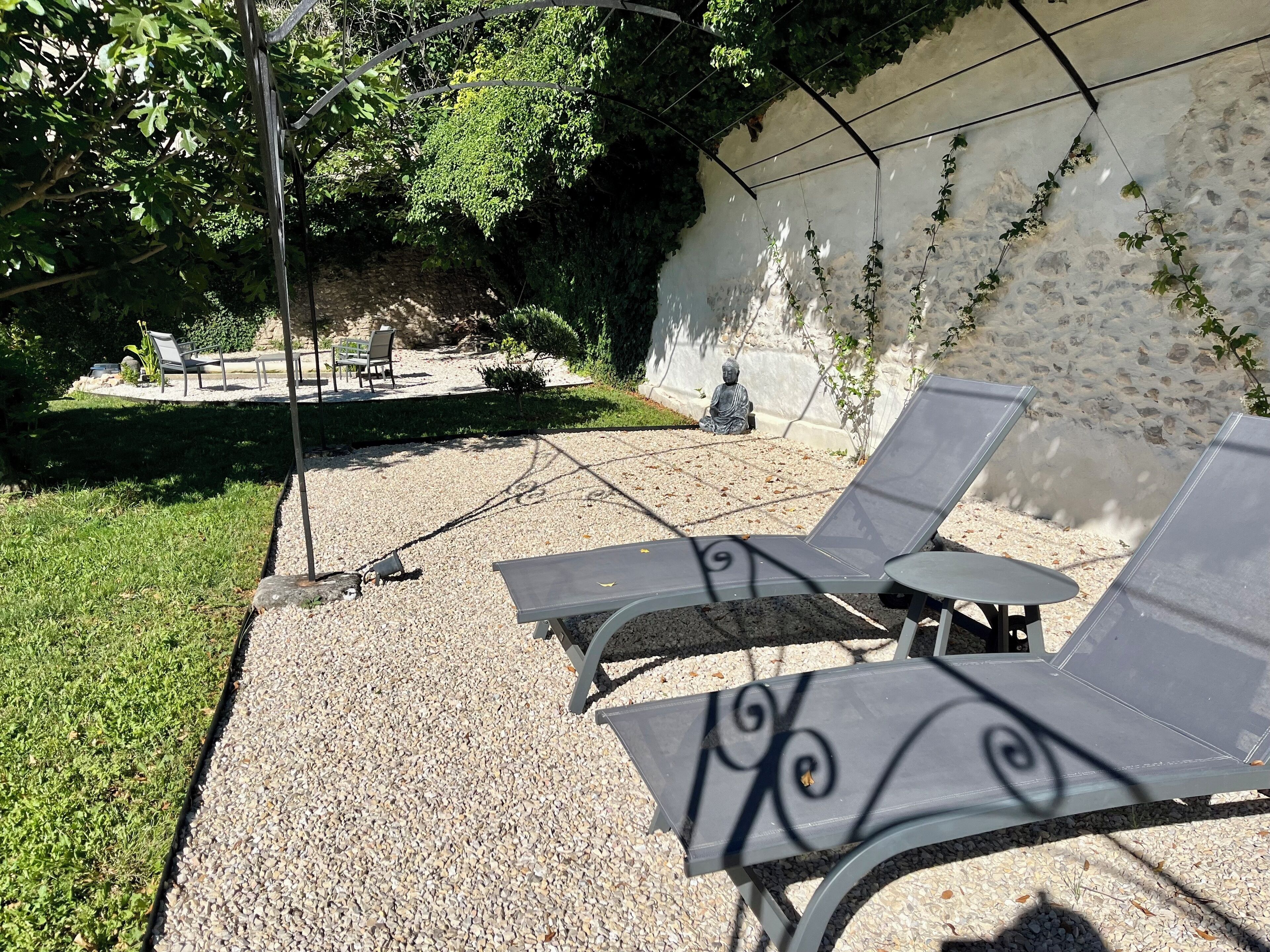 Un patio con dos sillones, una mesita y una estatua de Buda.