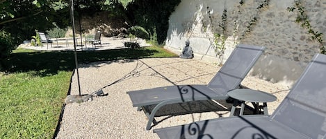 Un patio con dos sillones, una mesita y una estatua de Buda.