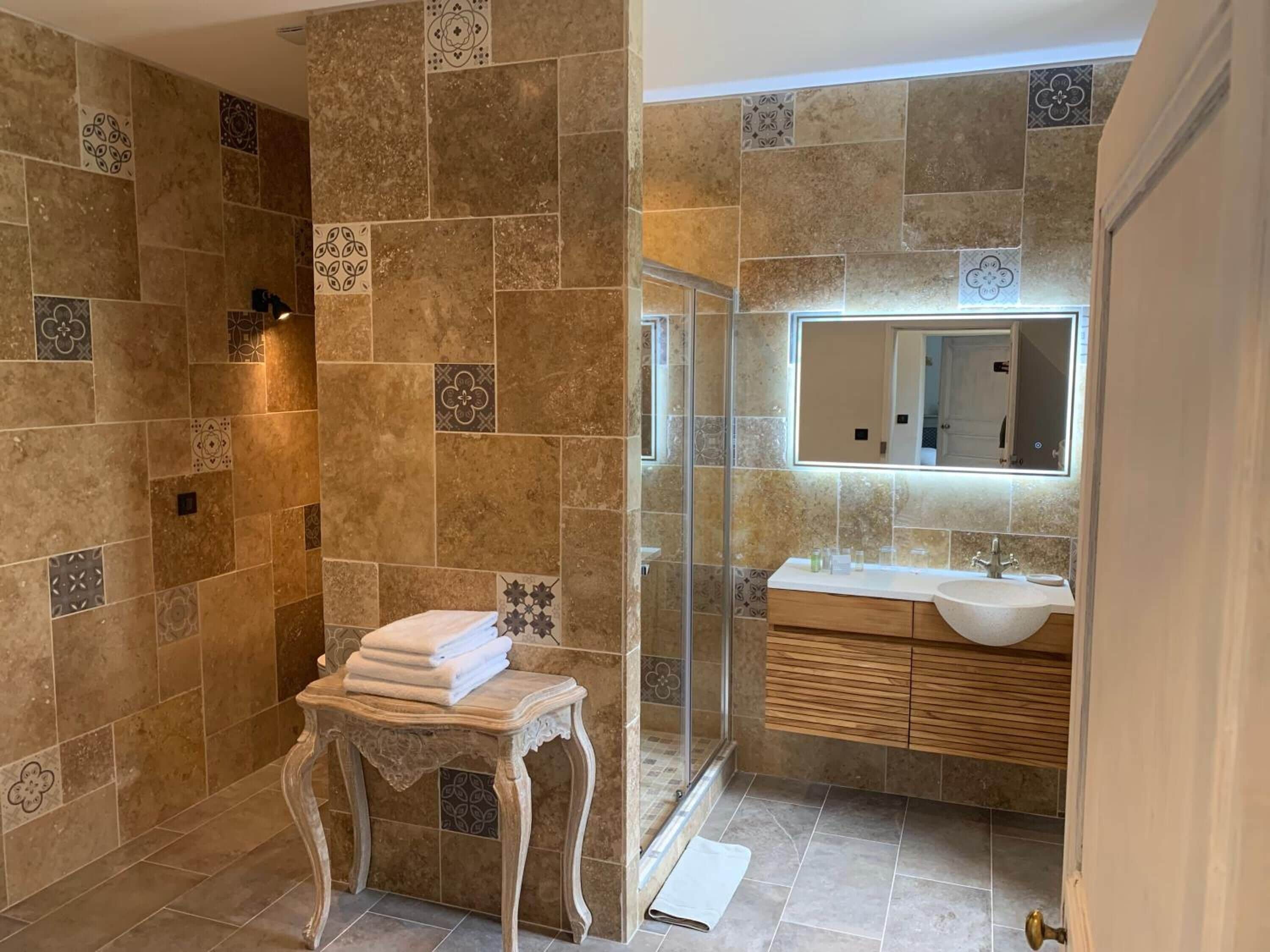 A bathroom with a glass-enclosed shower, a vanity with a sink, and a mirror above the sink.