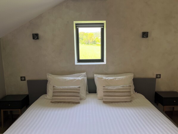 A bedroom with a large bed, two pillows, a window, and two nightstands. - Le Mas aux cedres (Lioux)