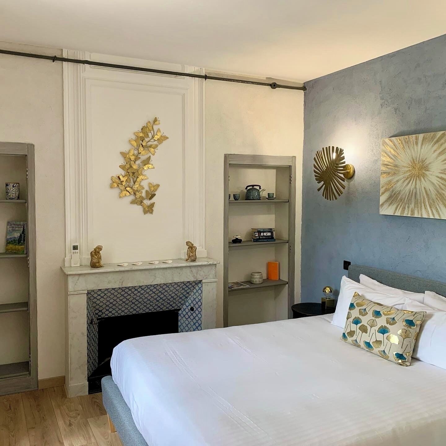 Quarto com cama, lareira, estante com livros e decoração na parede.